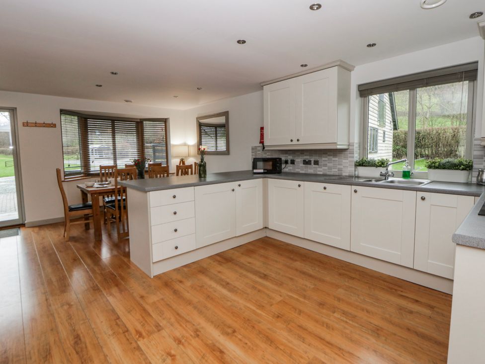 A kitchen with cabinets and a table at Maple Lodge in Knighton