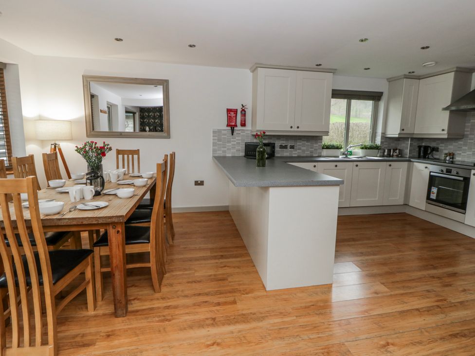 A kitchen and dining area with a table set for meals at Maple Lodge in Knighton