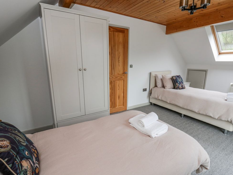 A bedroom with two beds and a wardrobe at Maple Lodge in Knighton
