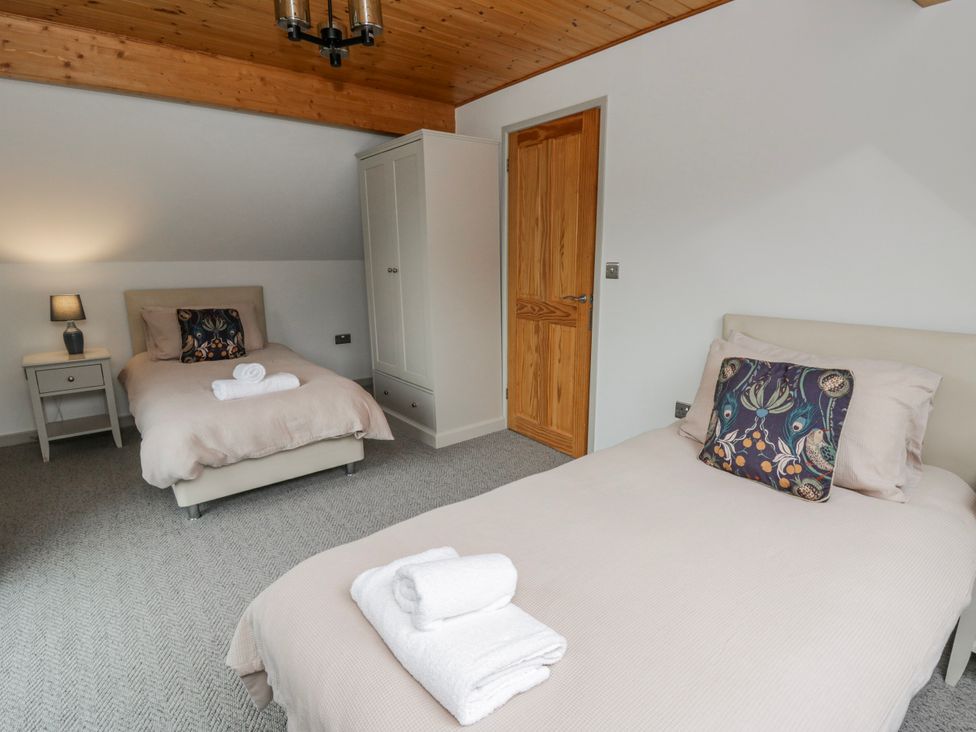 A bedroom with two beds and a wardrobe at Maple Lodge in Knighton