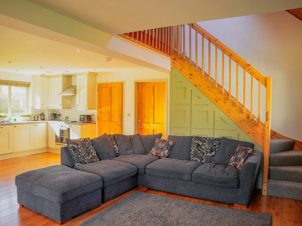A living room with a sofa and staircase at Maple Lodge Llangunllo