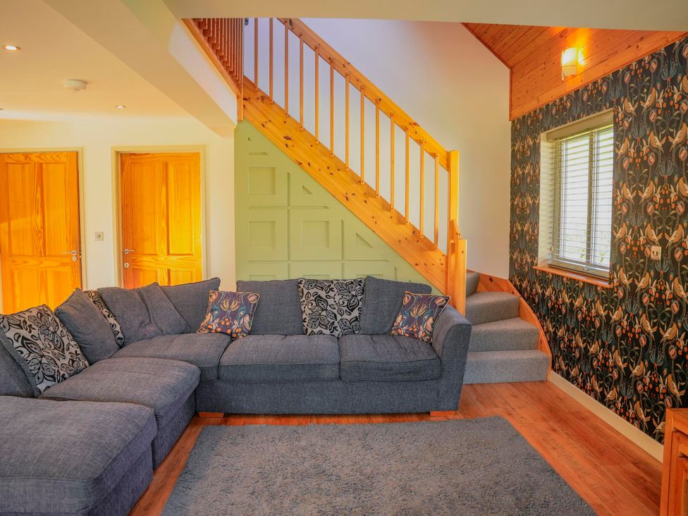 A living room with a sofa and staircase at Maple Lodge in Llangunllo