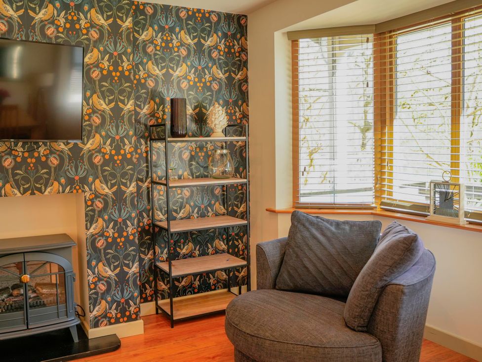 A living room with a television and bookshelf at Maple Lodge in Llangunllo