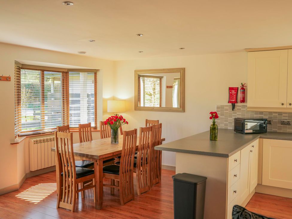A dining room with a table and chairs at Maple Lodge in Llangunllo