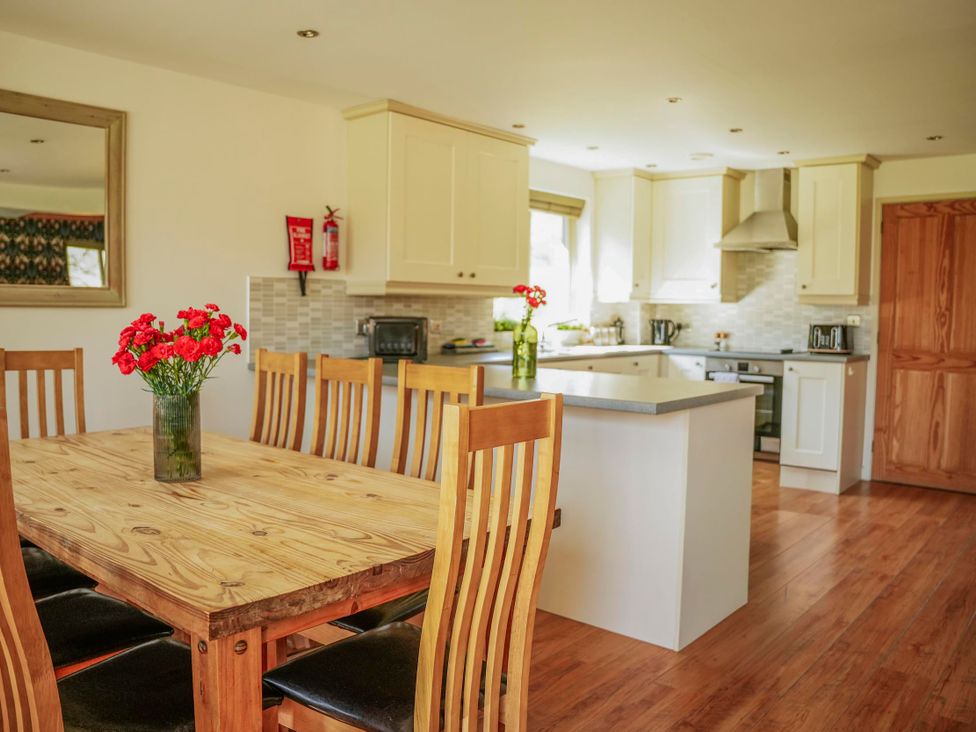 A kitchen with a dining table and chairs at Maple Lodge Llangunllo