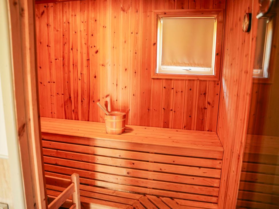 A sauna with wooden benches and a bucket at Maple Lodge in Llangunllo