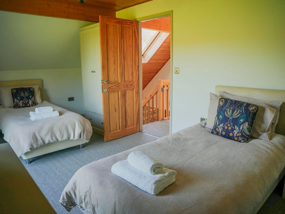 A bedroom with twin beds and a door leading to stairs at Maple Lodge in Llangunllo