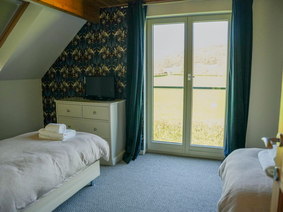 A bedroom with two beds and a television at Maple Lodge in Llangunllo