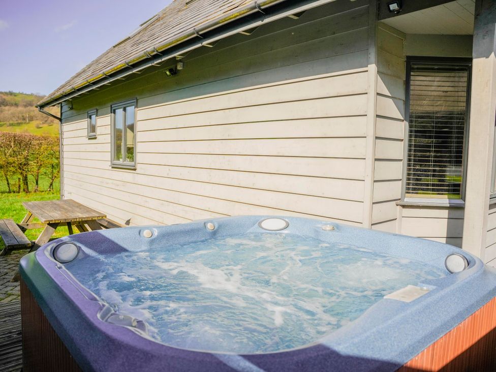 A hot tub on a wooden deck at Maple Lodge in Llangunllo
