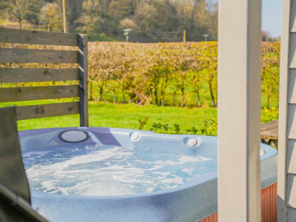 A hot tub with a wooden fence and grass area at Maple Lodge Llangunllo