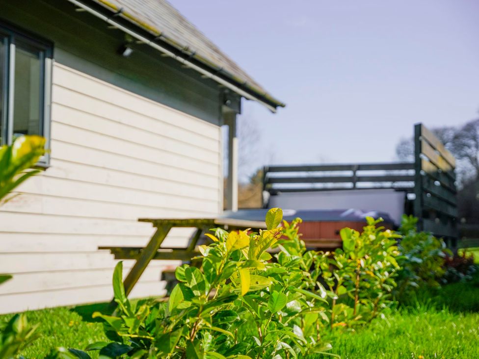 A garden with a deck and hot tub at Maple Lodge in Llangunllo