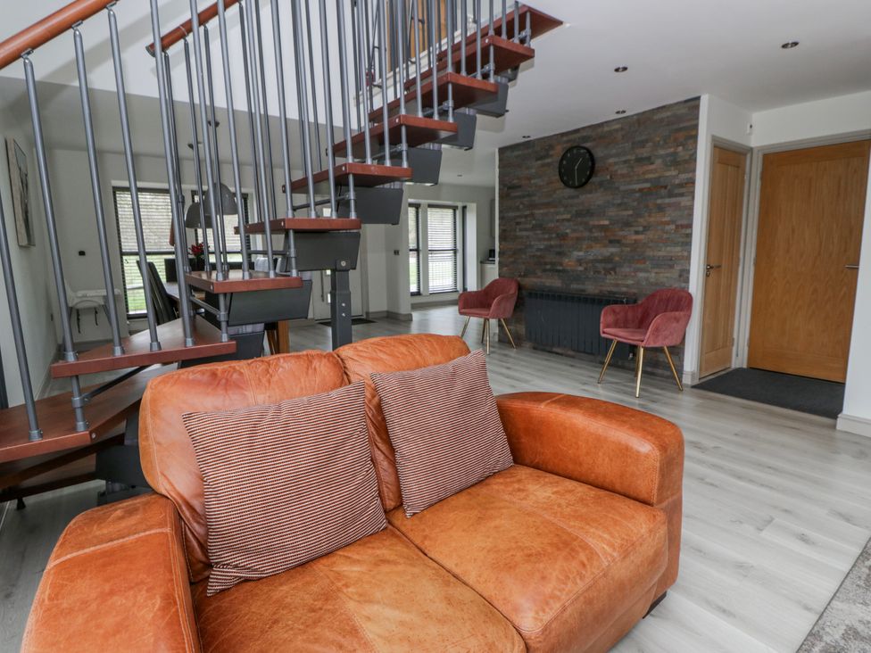 A living room with a staircase and sofa at Oak Lodge in Knighton