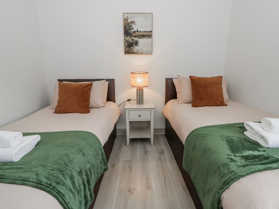 A bedroom with two beds and a lamp at Oak Lodge in Knighton