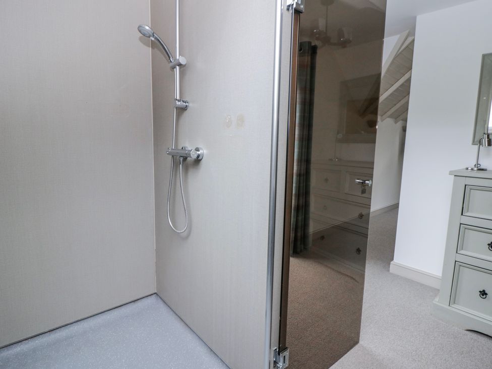 A shower area with a shower head and door at Oak Lodge in Knighton