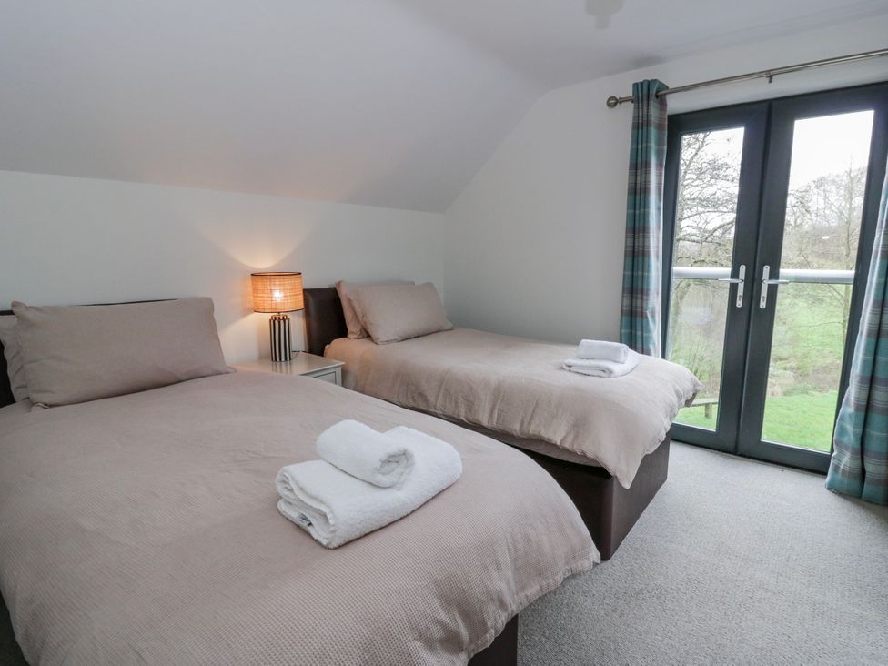A bedroom with two beds and a balcony door at Oak Lodge in Knighton