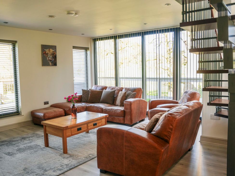 A living room with a sofa, coffee table, and staircase at Oak Lodge in Llangunllo