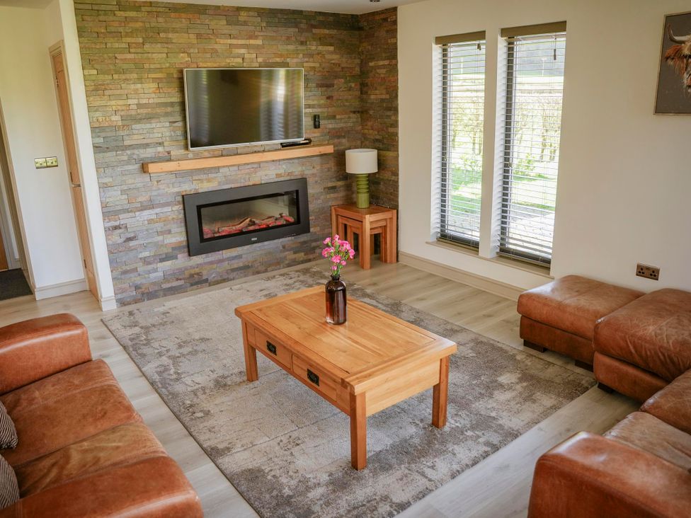 A living room with a fireplace and television at Oak Lodge in Llangunllo
