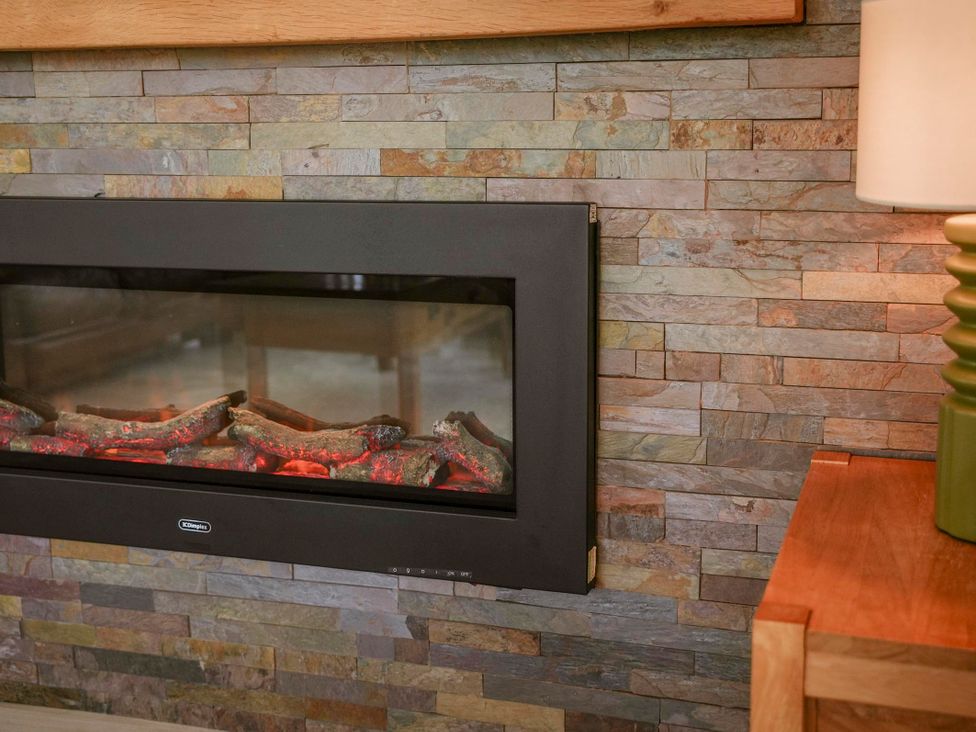 A fireplace with logs and a stone wall in Oak Lodge Llangunllo