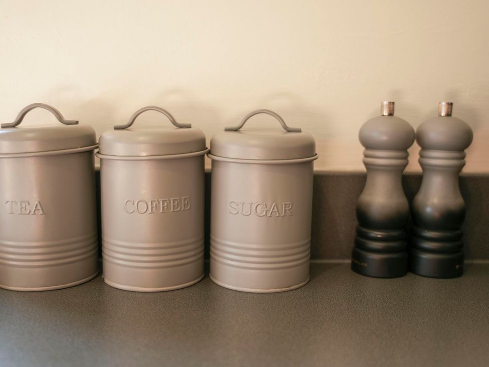 A kitchen countertop with containers for tea, coffee, sugar, and spice grinders at Oak Lodge in Llangunllo