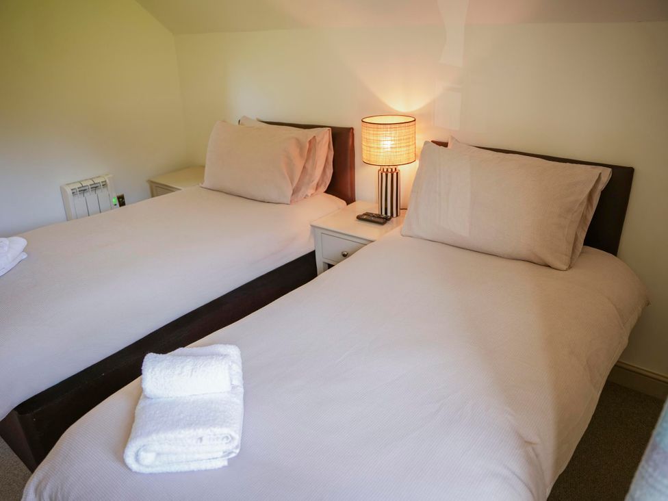 A bedroom with two single beds and a lamp at Oak Lodge in Llangunllo