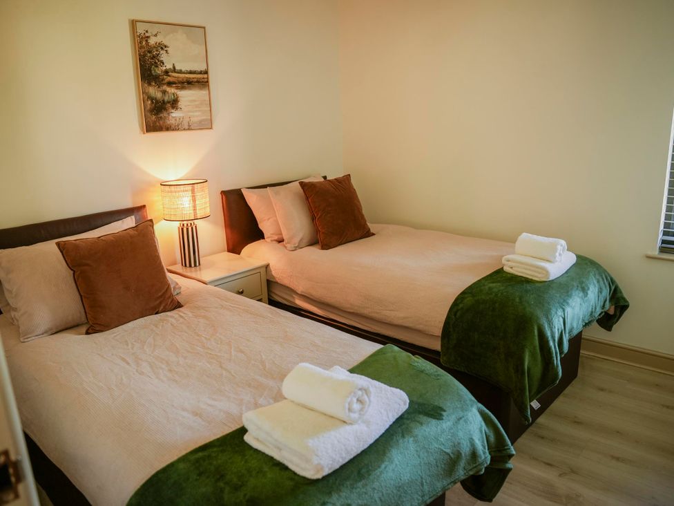 A bedroom with two beds and a lamp at Oak Lodge in Llangunllo