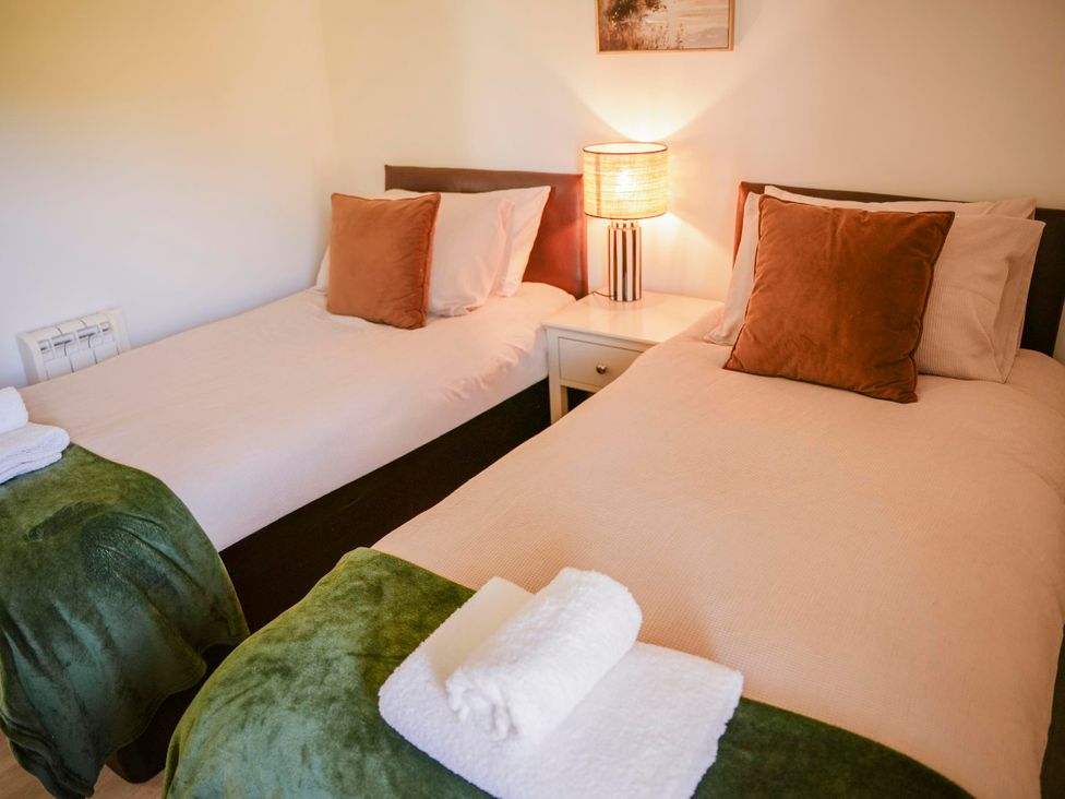 A bedroom with two beds and a lamp at Oak Lodge in Llangunllo