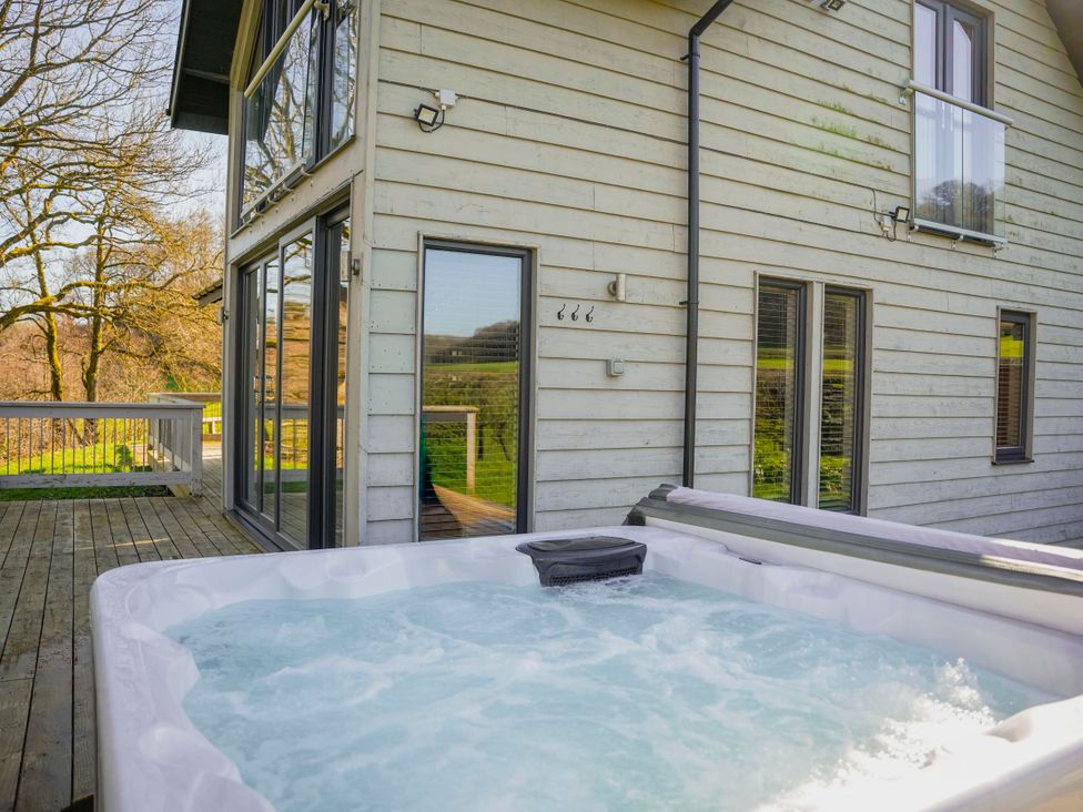 A hot tub next to a house on a wooden deck at Oak Lodge in Llangunllo
