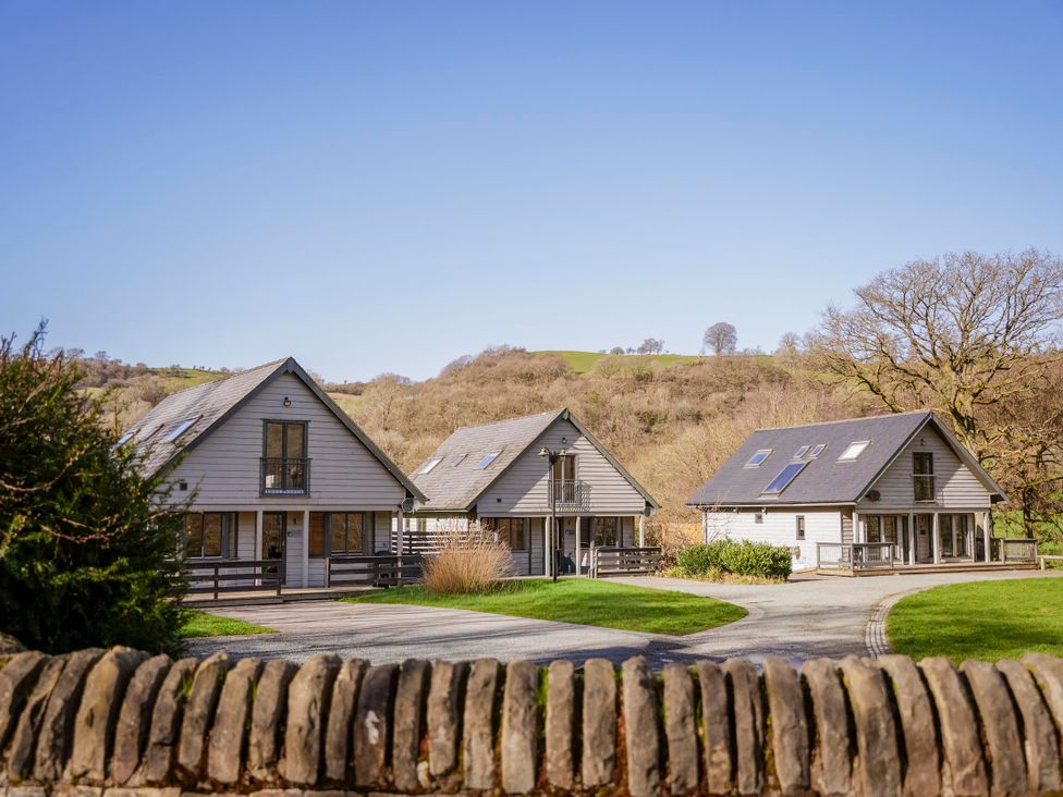 Three houses with green grass and trees at Oak Lodge in Llangunllo