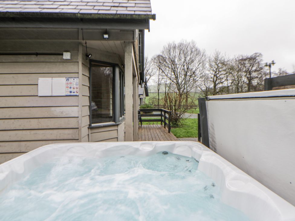 A hot tub near a wooden deck at Willow Lodge in Knighton