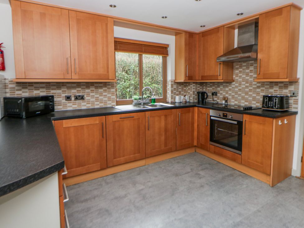 A kitchen with wooden cabinets and appliances at Willow Lodge in Knighton