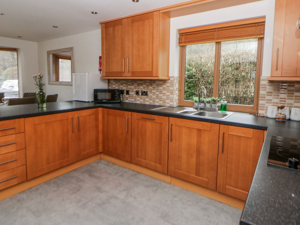 A kitchen with wooden cabinets and a sink at Willow Lodge Knighton