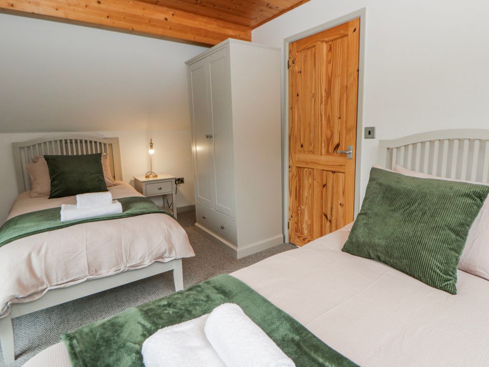 A bedroom with two beds and a wardrobe at Willow Lodge in Knighton