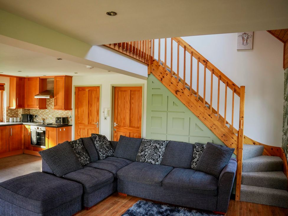 A living room with a sofa and kitchen area at Willow Lodge in Laceby