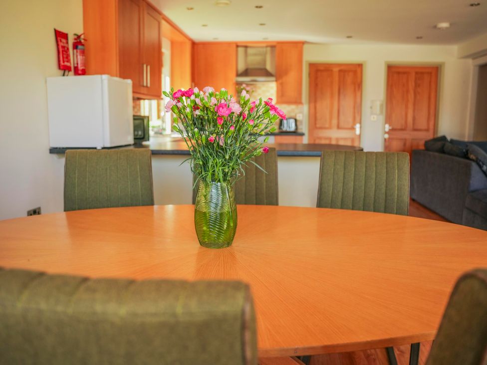 A dining room with a table and flowers at Willow Lodge in Laceby