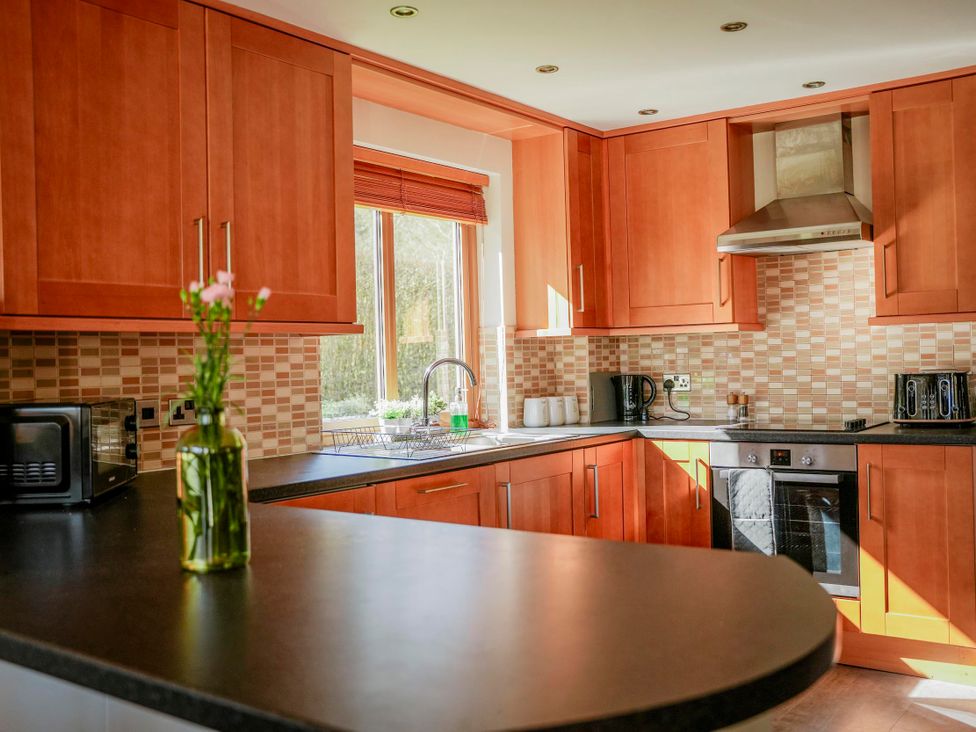 A kitchen with wooden cabinets, sink and appliances at Willow Lodge Laceby