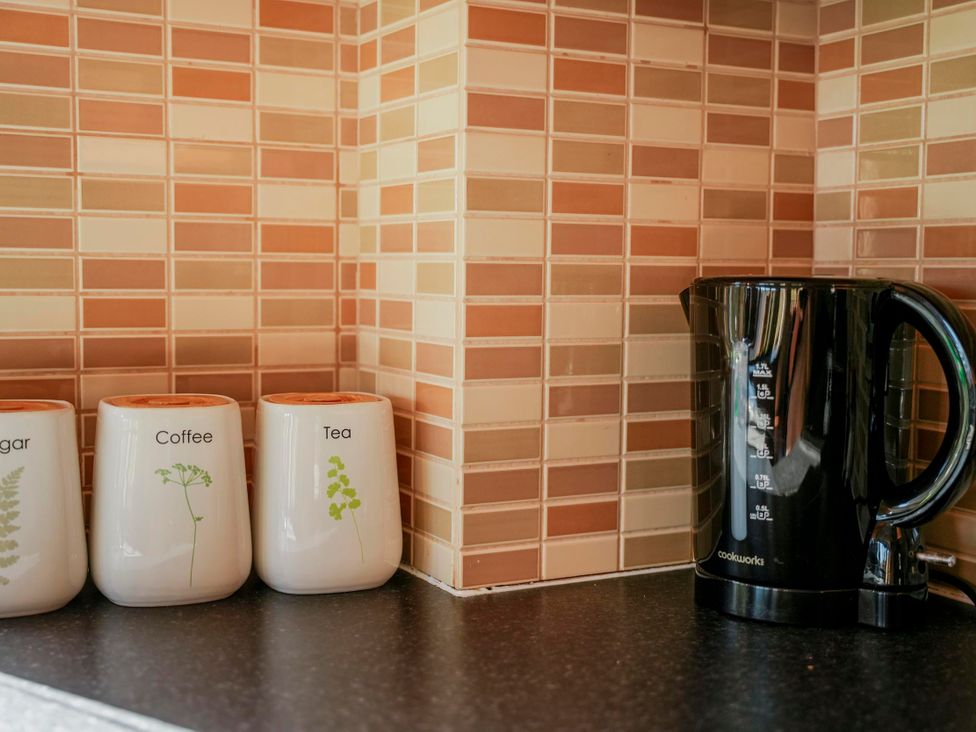A kitchen counter with a kettle and jars for sugar, coffee, and tea at Willow Lodge in Laceby