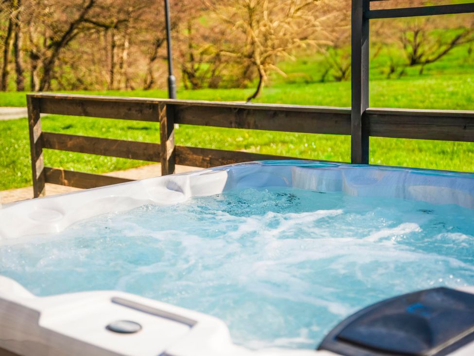 A hot tub with a view of the grass and trees at Willow Lodge in Laceby