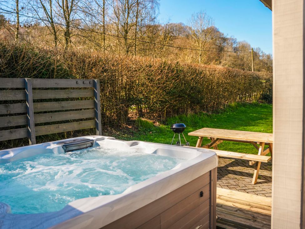 A hot tub with a grill and picnic table at Willow Lodge in Laceby