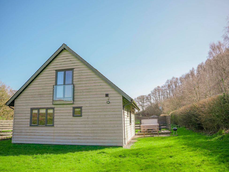 A wooden house with outdoor furniture and grill at Willow Lodge in Laceby