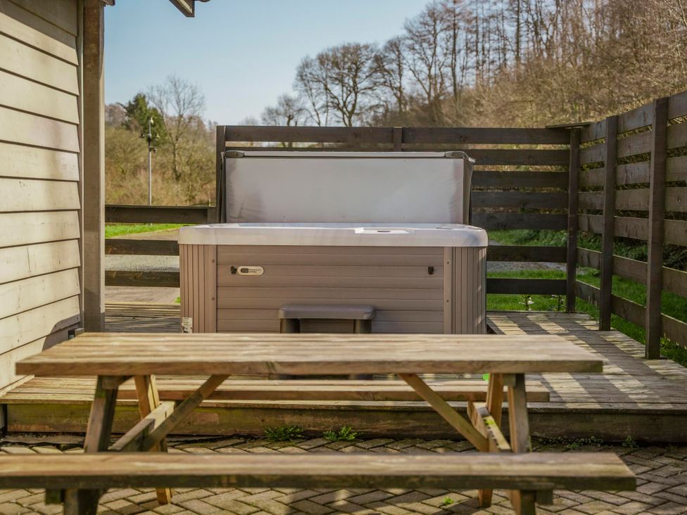 A hot tub and table on a deck at Willow Lodge in Laceby