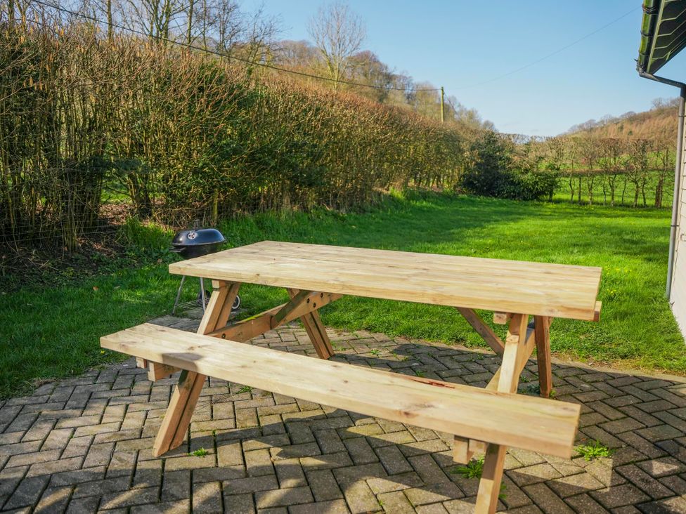 A wooden table and benches on a patio at Willow Lodge Laceby