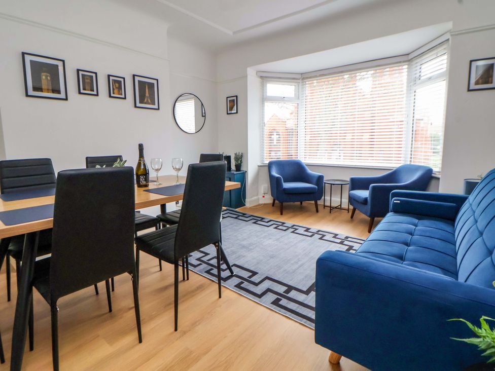 A living room with a dining area and blue furniture at Wallasey Village Escape by the Sea Wallasey