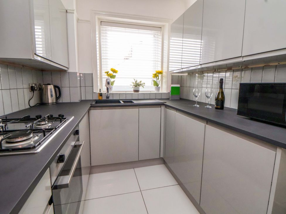 A kitchen with cabinets, sink, stove and microwave at Wallasey Village Escape by the Sea in Wallasey