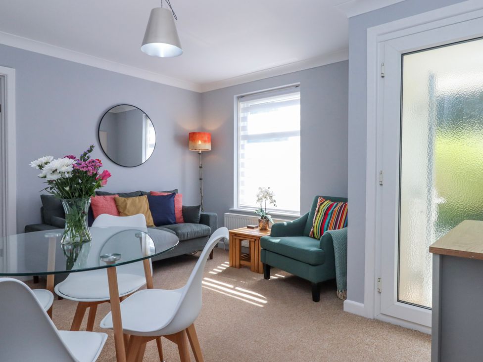 A living room with a glass table and seating at The Arches in Torquay