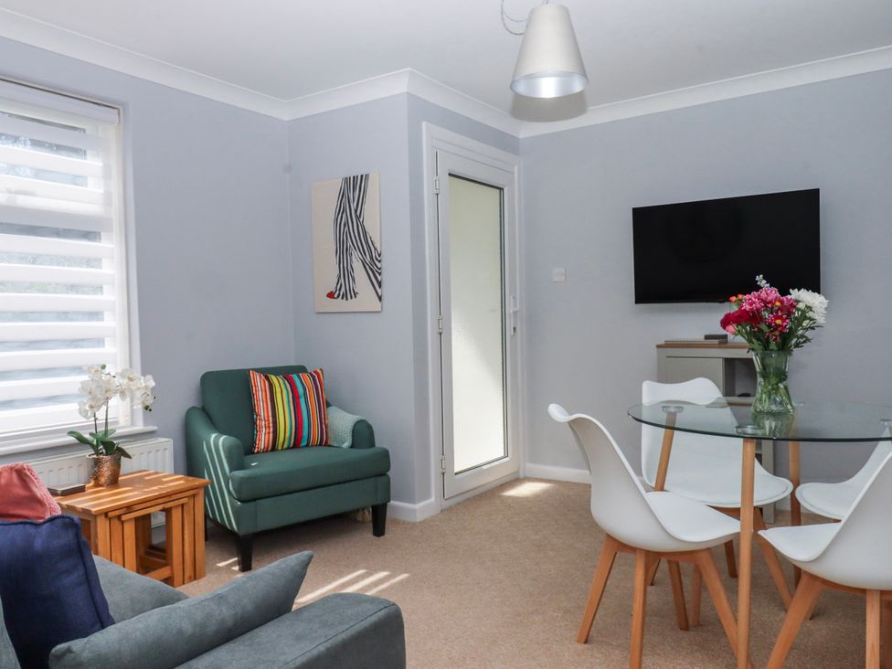 A living room with a table and chairs along with a tv at The Arches in Torquay