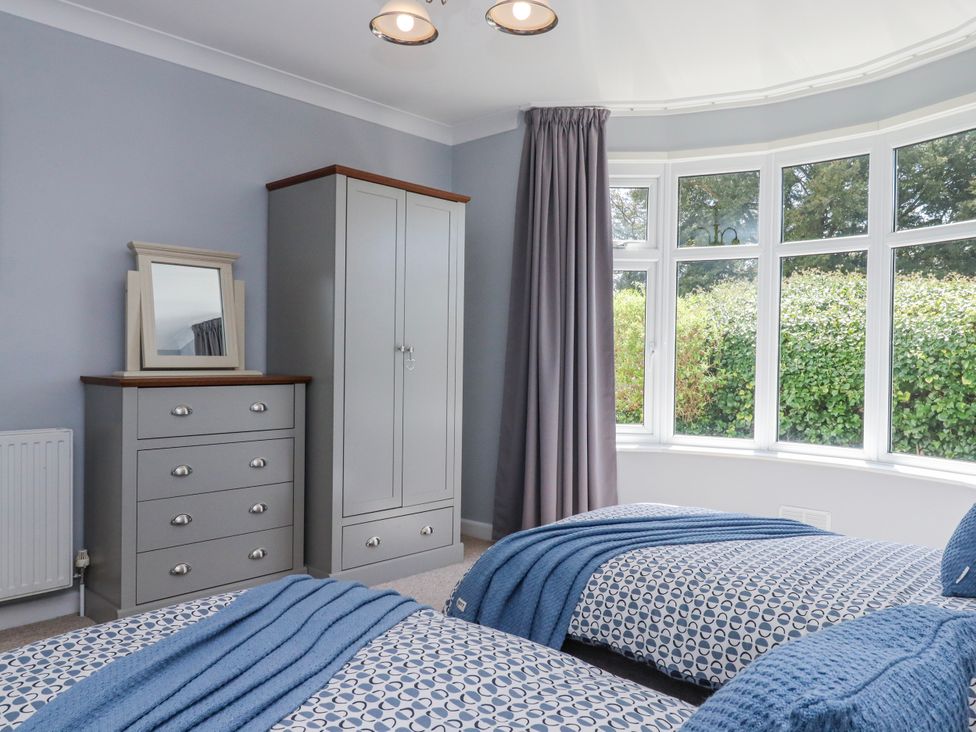 A bedroom with two beds, a wardrobe, and a chest of drawers at The Arches in Torquay