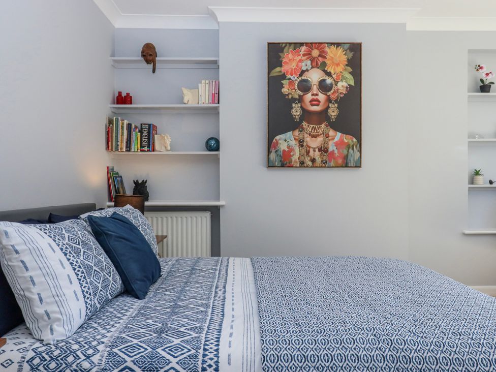 A bedroom with a bed and shelf containing books at The Arches in Torquay