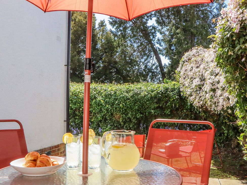An outdoor setting with a table, umbrella, pitcher, glasses, and croissants at The Arches in Torquay