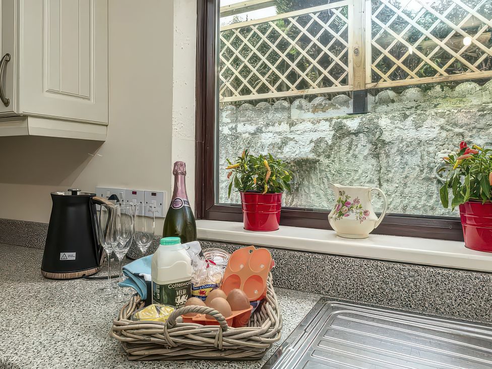 A kitchen counter with a kettle and basket of food items at Preswylfa