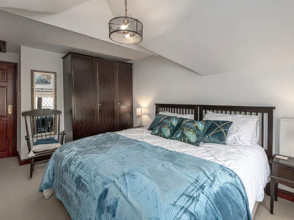 A bedroom with a bed, wardrobe, and chair at Preswylfa